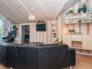 A modern living room with a sectional sofa, a television, and wooden panel walls.