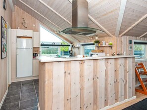 A modern kitchen with wooden paneling, a stainless steel range hood, and a large window providing a view of the outdoors.