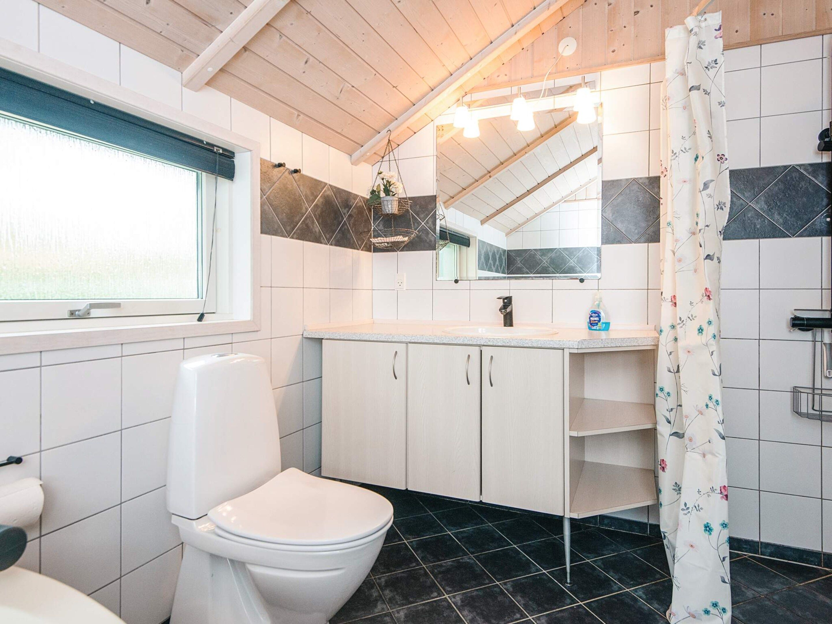 A bathroom with a toilet, a sink, a mirror, and a shower curtain.