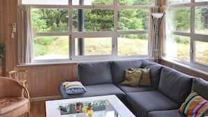 Un salon chaleureux avec un canapé gris, une table basse blanche et une chaise en bois.