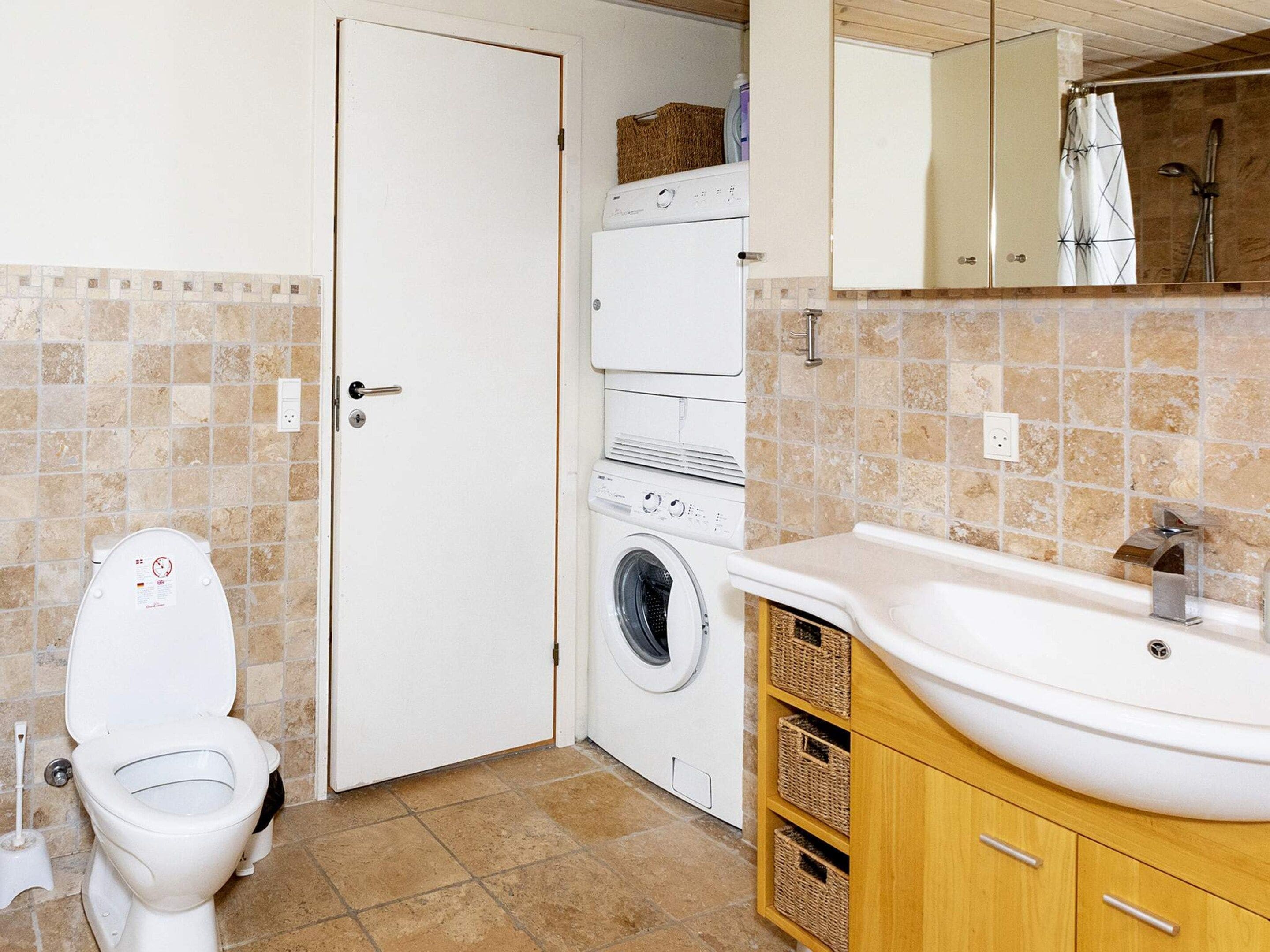 A compact bathroom with a toilet, washing machine, and sink.