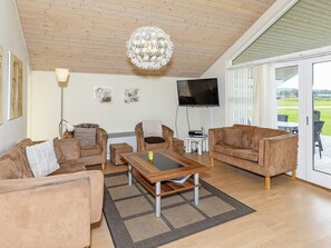 A living room with two sofas, a coffee table, a flat-screen TV, and a large window.