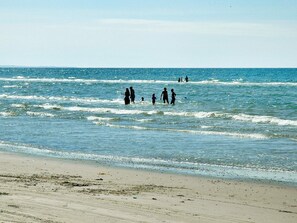 A beach with people walking in the water and on the sand. - 4 Star Holiday Home in Brovst (Brovst)