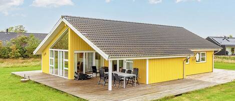A yellow building with a large patio area and a dining set.