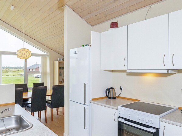 A modern kitchen with white cabinets, a stainless steel sink, and a built-in oven.