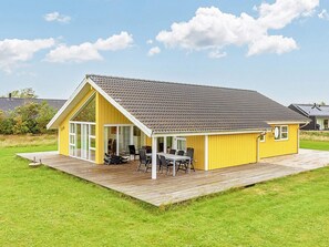 A yellow building with a large patio area and a dining set. - 4 Star Holiday Home in Brovst (Brovst)