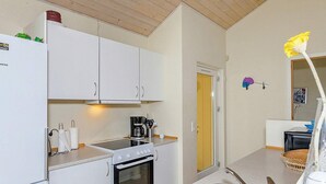 A compact kitchen with white cabinets, a built-in oven, a coffee maker, and a stainless steel sink.