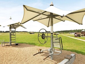 An outdoor gym with exercise equipment, a covered area, and a playground structure.