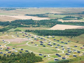 A residential area with houses arranged in a grid pattern, surrounded by green fields and a forested area. - 4 Star Holiday Home in Brovst (Brovst)