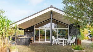 A modern outdoor deck with a wooden floor, white furniture, and a glass enclosure.