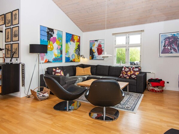 A modern living room with a sofa, two black chairs, a coffee table, and colorful abstract paintings on the walls. - 5 Star Holiday Home in Tarm (Tarm)