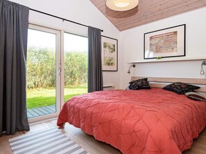 A bedroom with a large bed, a sliding glass door to a garden, and a framed map on the wall.