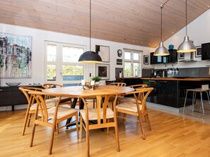 A modern kitchen with wooden flooring, a central island, pendant lighting, and a dining area with wooden chairs. - 5 Star Holiday Home in Tarm (Tarm)