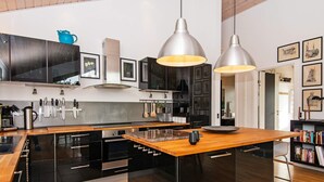 A modern kitchen with black cabinetry, stainless steel appliances, and a wooden island.