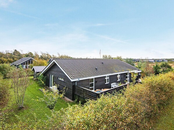 A modern house with a dark exterior, a sloped roof, and a small deck.
