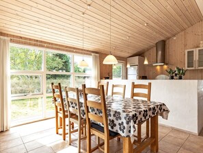 A wooden interior with a dining table, chairs, a kitchen area, and large windows. - 4 Star Holiday Home in Albaek (Aalbaek)