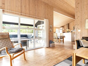 A wooden interior with a dining area, kitchen, and seating space.