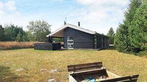 A modern house with a deck, a chimney, and a large tree nearby. - 4 Star Holiday Home in Albaek (Aalbaek)