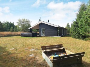 A modern house with a deck, a chimney, and a large tree nearby. - 4 Star Holiday Home in Albaek (Aalbaek)