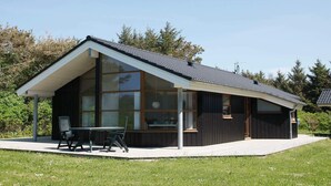 Une maison moderne dotée d’une grande baie vitrée, d’un patio couvert et d’une façade en bois.