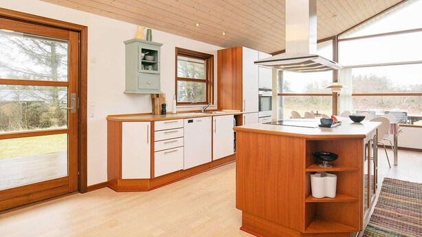 Une cuisine moderne avec des meubles en bois, un îlot central intégré et une grande fenêtre qui laisse entrer la lumière naturelle.