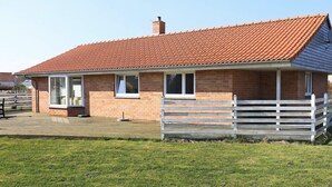A single-story brick house with a red-tiled roof, a front porch with a white fence, and a paved driveway. - 4 Star Holiday Home in Humble (Sydlangeland)