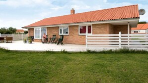 A single-story brick house with a red-tiled roof, a white fence, and a patio with outdoor furniture. - 4 Star Holiday Home in Humble (Sydlangeland)