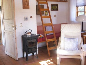 A room with a wooden door, a small stove, a chair with a cushion, a ladder, and a window with blinds. - 4 Star Holiday Home in Bramming (Bramming)