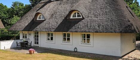 A white building with a thatched roof and multiple windows.