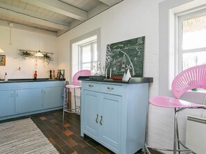 A kitchen with light blue cabinets, a pink chair, and a green chalkboard with writing. - 4 Star Holiday Home in Asperup (Middelfart)