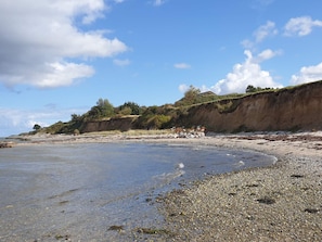 A coastal beach with pebbles, a cliff, and sparse vegetation. - 4 Star Holiday Home in Asperup (Middelfart)