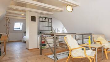 Ein großzügiges Loft mit hohen Decken, einer Zwischenebene und einer Essecke mit Holztischen und -stühlen.