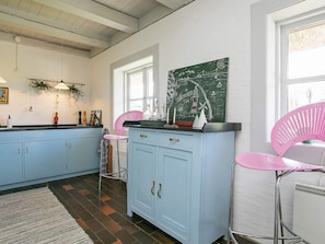 A kitchen with light blue cabinets, a pink chair, and a green chalkboard with writing. - 4 Star Holiday Home in Asperup (Middelfart)