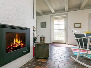 A room with a fireplace, a door leading outside, a rocking chair, and a colorful rug. - 4 Star Holiday Home in Asperup (Middelfart)
