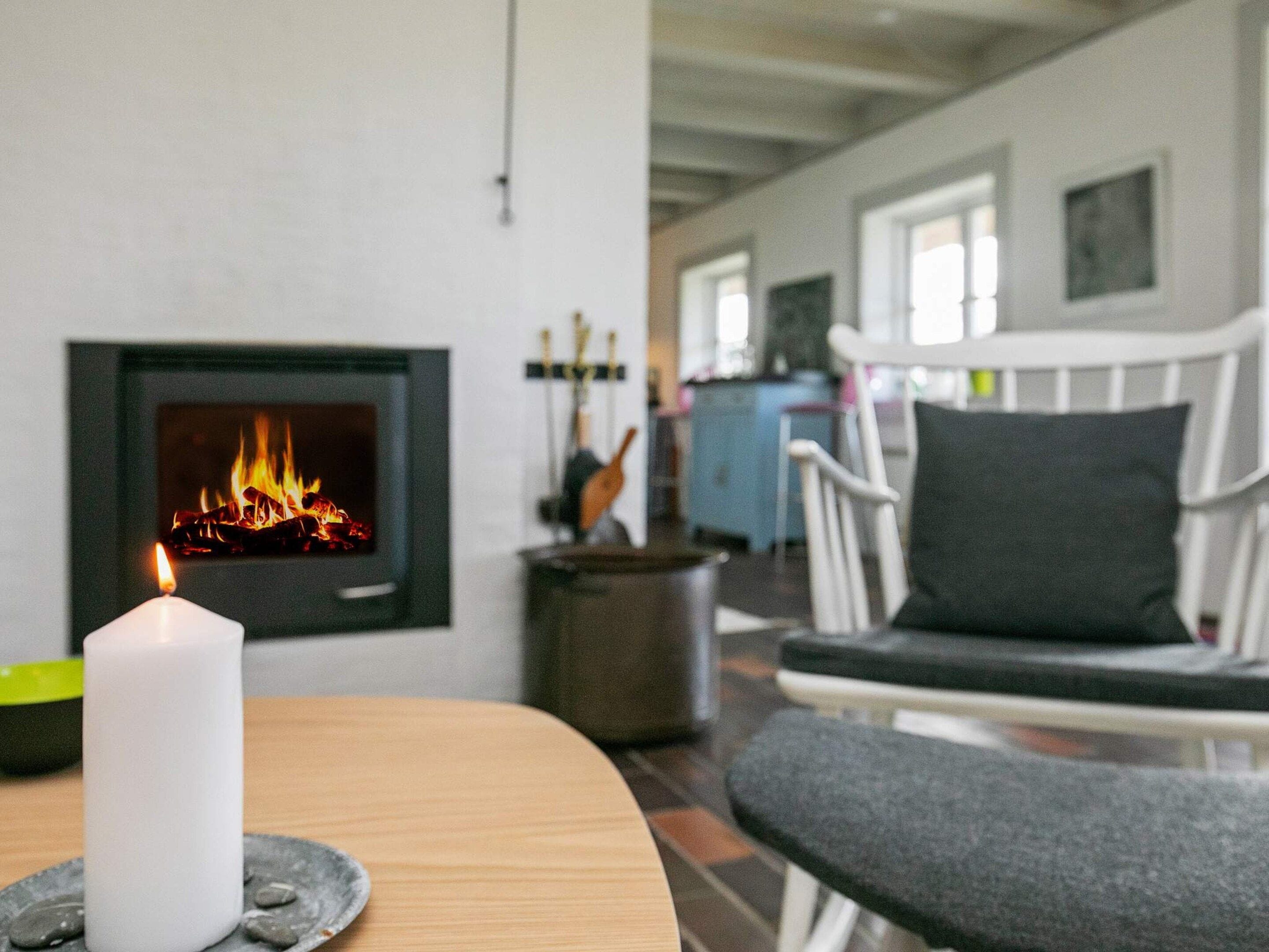 A room with a fireplace, a lit candle, and a seating area with a chair and a bench.