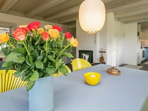 A dining area with a table set for two, a vase of flowers, and a yellow chair. - 4 Star Holiday Home in Asperup (Middelfart)
