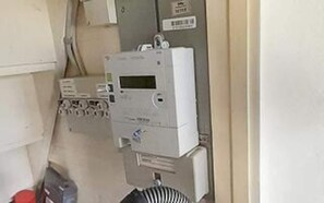 A utility meter with a digital display, a control panel with multiple switches, and a cable management box.