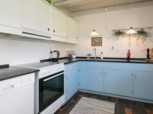 A kitchen with white cabinets, a black countertop, a stove, and a sink.