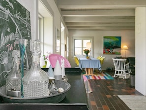 Un comedor con una mesa dispuesta para dos personas, una pizarra con escritura y una ventana con vistas.