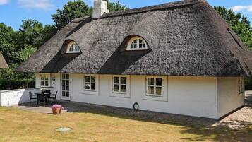 A white building with a thatched roof and multiple windows.