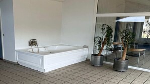A spacious bathroom with a large white bathtub, two potted plants, and a glass shower enclosure. - Modern Pool House With View - By Traum Ferienwohnungen (Hjørring)