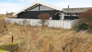 A modern house with a sloped roof, a fenced yard, and a small garden area. - Modern Pool House With View - By Traum Ferienwohnungen (Hjørring)