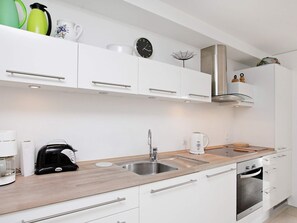 A modern kitchen with white cabinetry, stainless steel appliances, and a wooden countertop. - 4 Star Holiday Home in Bogense (Bogense)