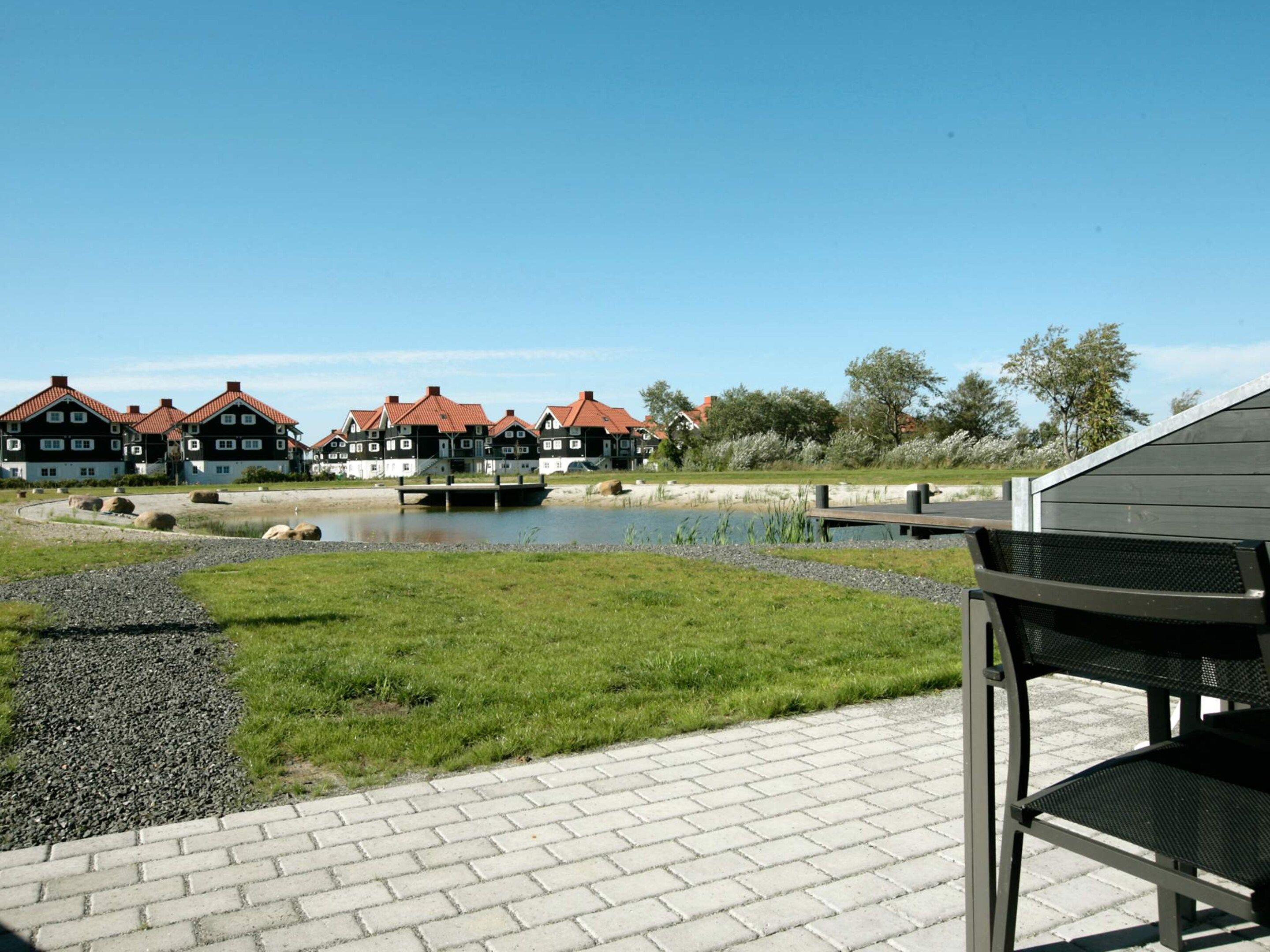 A riverside view with traditional houses, a wooden dock, and a paved walkway.
