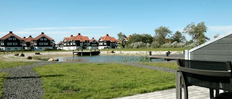 A riverside view with traditional houses, a wooden dock, and a paved walkway.