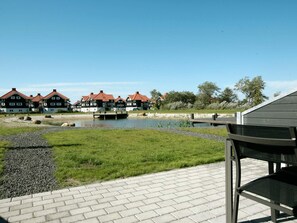 A riverside view with traditional houses, a wooden dock, and a paved walkway. - 4 Star Holiday Home in Bogense (Bogense)