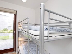 Un letto a castello con ringhiere in metallo e una finestra che si affaccia su un edificio e del verde circostante.
