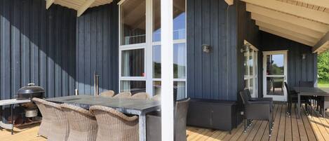 An outdoor deck with a grill, wicker furniture, and a table.