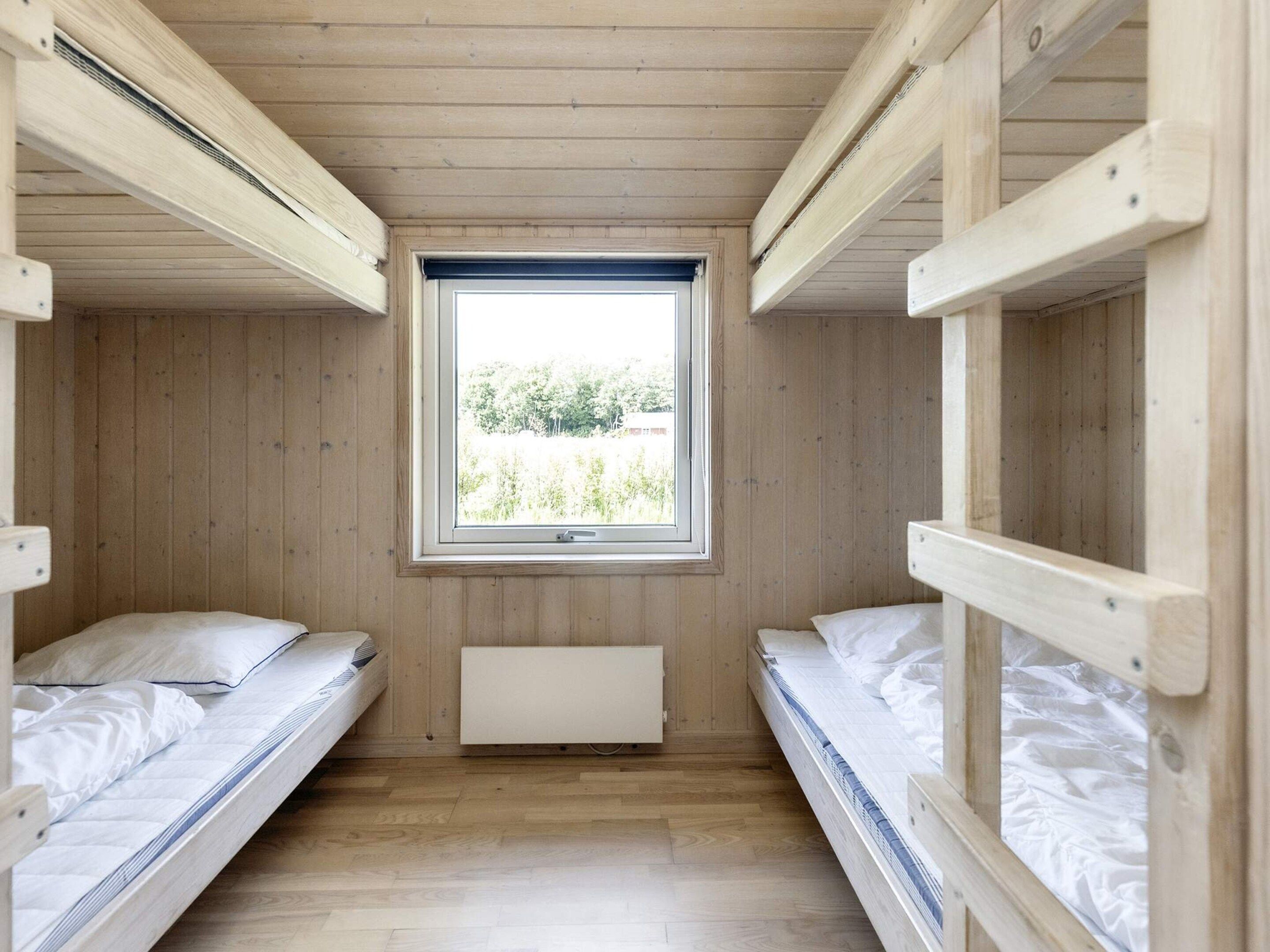 Una habitación con dos literas, una ventana y un radiador.