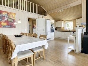 A spacious kitchen with white cabinets, a dining area with a table and chairs, and a wooden ceiling.